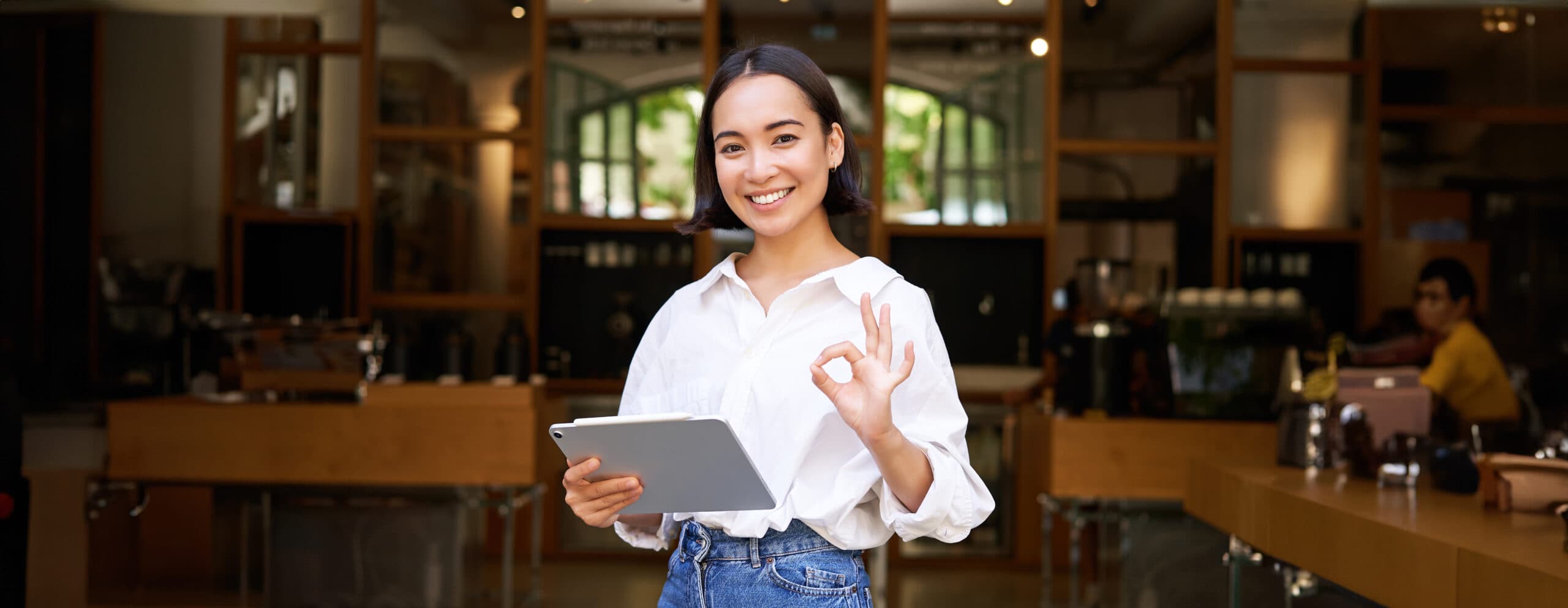 young-female-entrepreneur-cafe-manager-standing-with-tablet-showing-approval-recommending-scaled